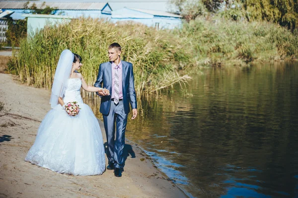 Bruid en bruidegom op huwelijksdag buiten lopen op lente aard. bruidspaar, gelukkig jonggehuwde vrouw en man omarmen in groen park. liefdevolle bruidspaar buiten — Stockfoto