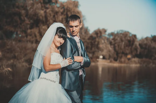 Manželský pár líbání na pláži řeka. Nevěsta ženich Svatební pár chůze venku na rivershore — Stock fotografie