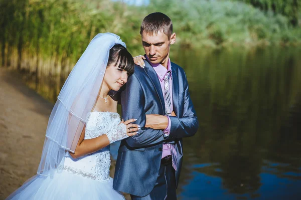 Manželský pár líbání na pláži řeka. Nevěsta ženich Svatební pár chůze venku na rivershore — Stock fotografie