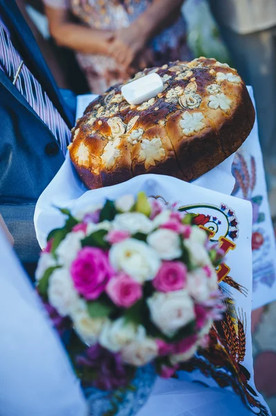 Pengantin pria memegang sepotong roti bundar tradisional dan pengantin wanita — Stok Foto