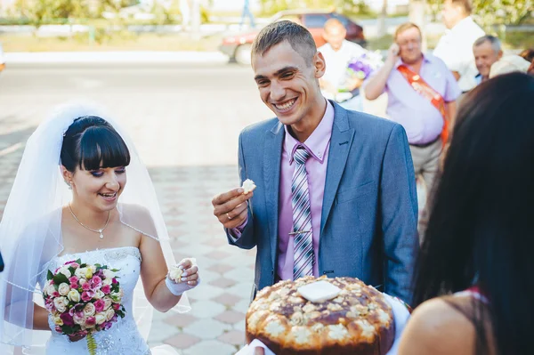 Groom segurando fatia de pão redondo de casamento tradicional e noiva — Fotografia de Stock