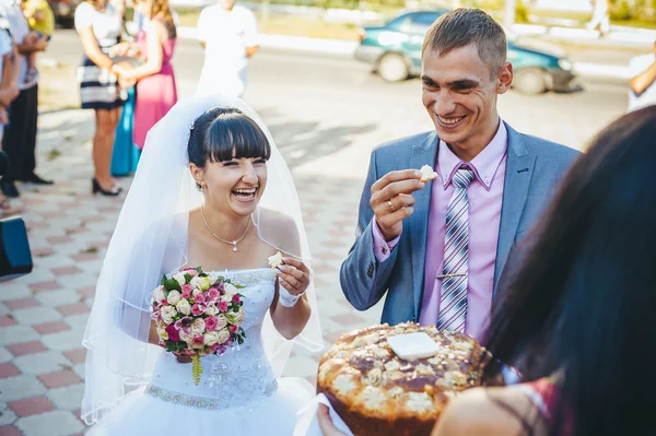 Novio sosteniendo rebanada de pan redondo de boda tradicional y novia — Foto de Stock