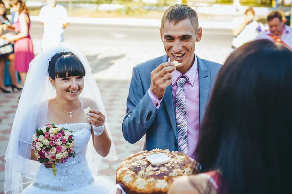 Groom holding slice of traditional wedding round loaf and bride — Stock Photo, Image