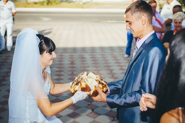 Groom holding slice of traditional wedding round loaf and bride — Stock Photo, Image