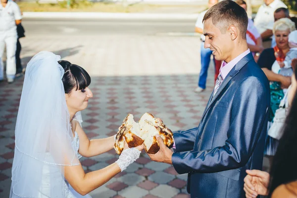 Groom holding slice of traditional wedding round loaf and bride — Stock Photo, Image