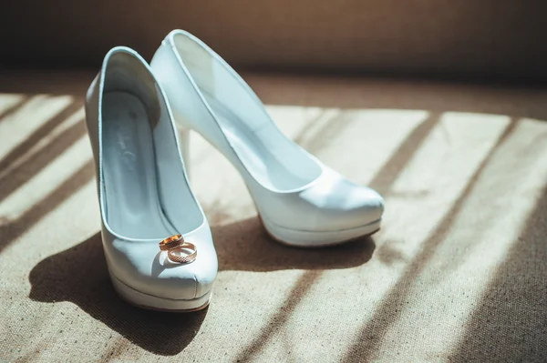 Beyaz gelinlik ayakkabısında iki altın yüzük var. — Stok fotoğraf