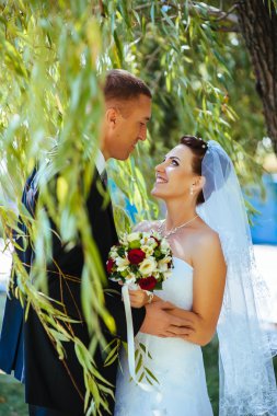 Gelin ve damat, düğün günü açık havada yürüyüş Doğa bahar. mutlu yeni evli kadın ve erkek yeşil park kucaklayan gelin çift. sevgi dolu evlilik çift açık.