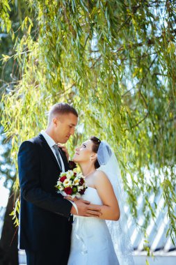 Gelin ve damat, düğün günü açık havada yürüyüş Doğa bahar. mutlu yeni evli kadın ve erkek yeşil park kucaklayan gelin çift. sevgi dolu evlilik çift açık.