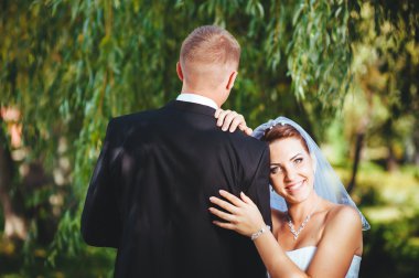 Gelin ve damat, düğün günü açık havada yürüyüş Doğa bahar. mutlu yeni evli kadın ve erkek yeşil park kucaklayan gelin çift. sevgi dolu evlilik çift açık.