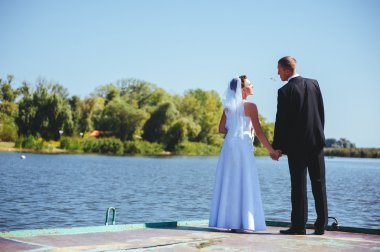 Deniz kenarında bir düğün. Balayı. Gelin ve damat Gölü kıyısına sarılma. damat ve gelin yeşil bir gölde sarılma. Damat ve gelin bir parkta. gelinlik. Gelin düğün buket çiçek.