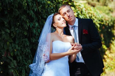 Gelin ve damat, düğün günü açık havada yürüyüş Doğa bahar. mutlu yeni evli kadın ve erkek yeşil park kucaklayan gelin çift. sevgi dolu evlilik çift açık.