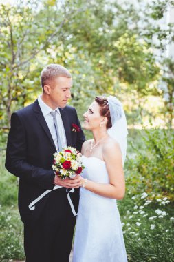 Gelin ve damat, düğün günü açık havada yürüyüş Doğa bahar. mutlu yeni evli kadın ve erkek yeşil park kucaklayan gelin çift. sevgi dolu evlilik çift açık.