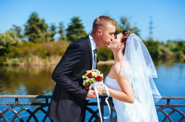 Deniz kenarında bir düğün. Balayı. Gelin ve damat Gölü kıyısına sarılma. damat ve gelin yeşil bir gölde sarılma. Damat ve gelin bir parkta. gelinlik. Gelin düğün buket çiçek.