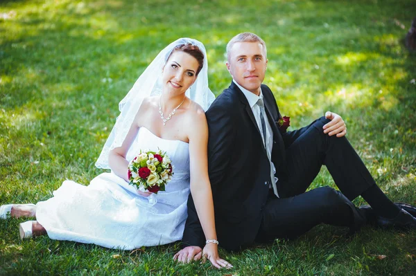 Noiva e noivo no dia do casamento andando ao ar livre na natureza de primavera. Casal nupcial, mulher recém-casada feliz e homem abraçando no parque verde. Casal de amor ao ar livre . — Fotografia de Stock