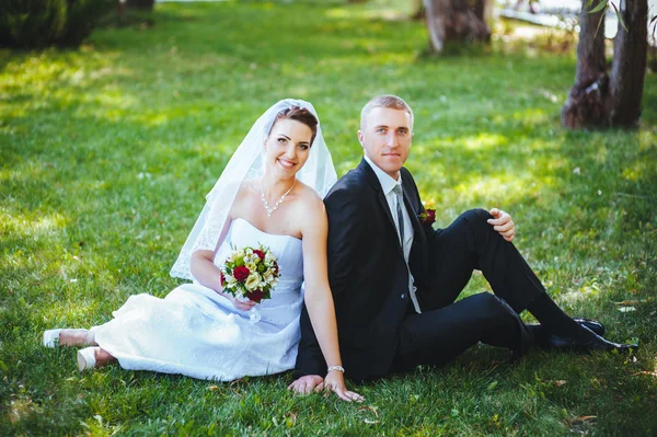 Noiva e noivo no dia do casamento andando ao ar livre na natureza de primavera. Casal nupcial, mulher recém-casada feliz e homem abraçando no parque verde. Casal de amor ao ar livre . — Fotografia de Stock