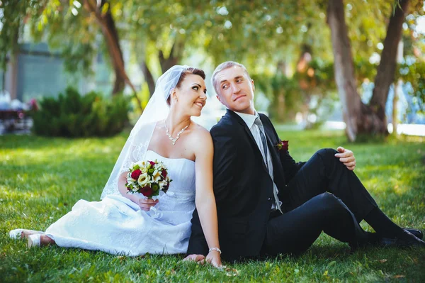 Novia y novio en el día de la boda caminando al aire libre en la naturaleza de primavera. Pareja nupcial, feliz mujer recién casada y hombre abrazándose en el parque verde. Amar pareja de boda al aire libre . — Foto de Stock