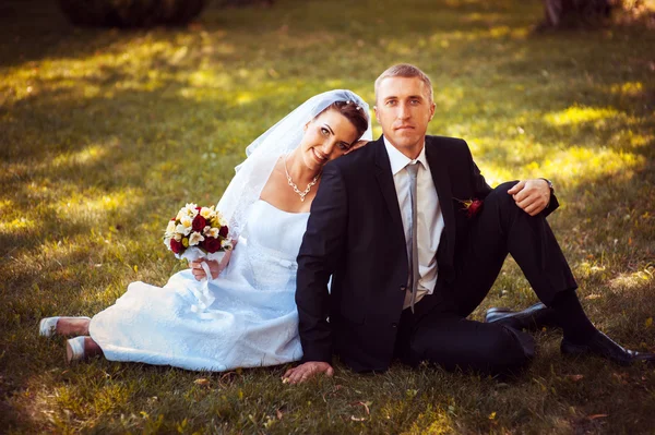 Noiva e noivo no dia do casamento andando ao ar livre na natureza de primavera. Casal nupcial, mulher recém-casada feliz e homem abraçando no parque verde. Casal de amor ao ar livre . — Fotografia de Stock