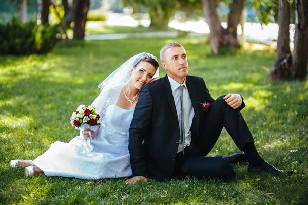 Novia y novio en el día de la boda caminando al aire libre en la naturaleza de primavera. Pareja nupcial, feliz mujer recién casada y hombre abrazándose en el parque verde. Amar pareja de boda al aire libre . — Foto de Stock