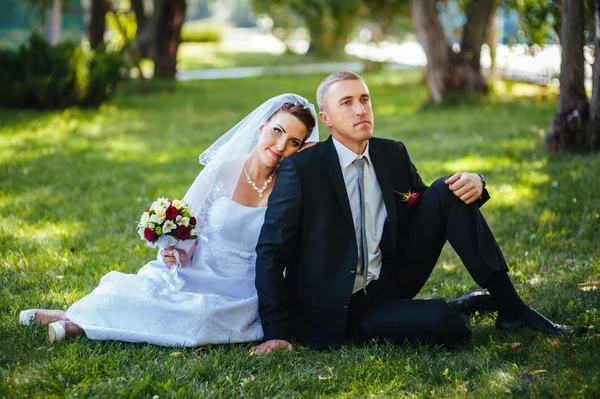 Novia y novio en el día de la boda caminando al aire libre en la naturaleza de primavera. Pareja nupcial, feliz mujer recién casada y hombre abrazándose en el parque verde. Amar pareja de boda al aire libre . — Foto de Stock