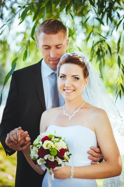 Novia y novio en el día de la boda caminando al aire libre en la naturaleza de primavera. Pareja nupcial, feliz mujer recién casada y hombre abrazándose en el parque verde. Amar pareja de boda al aire libre . —  Fotos de Stock