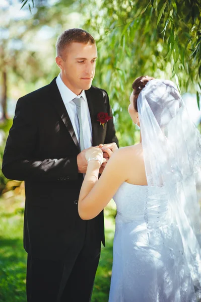 Noiva e noivo no dia do casamento andando ao ar livre na natureza de primavera. Casal nupcial, mulher recém-casada feliz e homem abraçando no parque verde. Casal de amor ao ar livre . — Fotografia de Stock