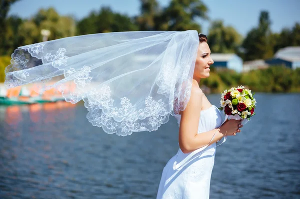 Portrait of beautiful young bride holding bright bouquet of flowers in hands. wedding celebration. reception. nature green background. woman alone outdoors in park — Stock Photo, Image