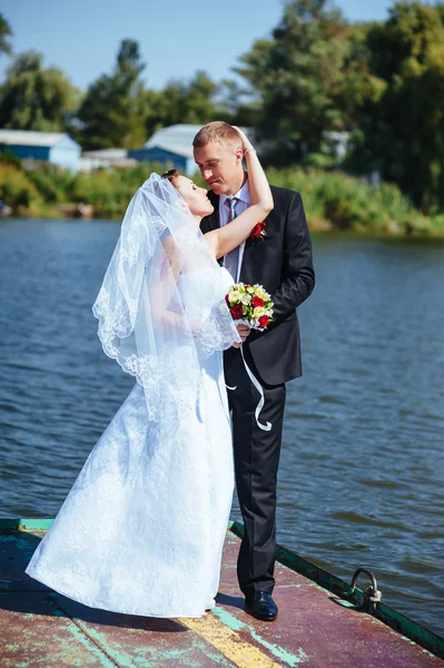 Svatba u moře. Líbánky. Nevěsta a ženich objímání na břehu jezera. ženich a nevěsta objímání na zelené jezero. Ženich a nevěsta v parku. svatební šaty. Svatební Svatební kytice. — Stock fotografie