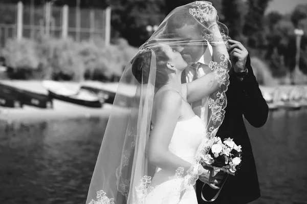 Un mariage près de la mer. Lune de miel. Les mariés se câlinent sur la rive du lac. marié et mariée étreignant sur un lac vert. Groom and Bride dans un parc. robe de mariée. Bouquet de mariage nuptial de fleurs . — Photo