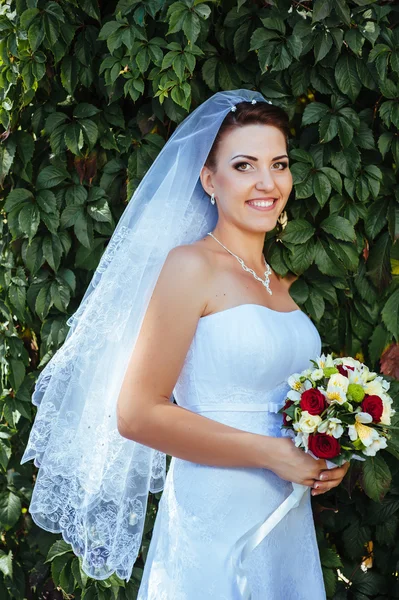 Gyönyörű fiatal menyasszony kezében fényes csokor virág, kezében portréja. lakodalomban. recepció. természet zöld háttér. nő egyedül szabadban park — Stock Fotó