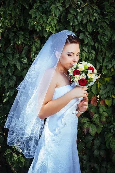 Retrato de hermosa novia joven sosteniendo ramo brillante de flores en las manos. celebración de la boda. recepción. naturaleza fondo verde. mujer sola al aire libre en el parque —  Fotos de Stock