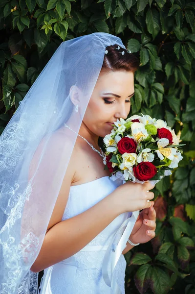 Portrait de belle jeune mariée tenant un bouquet lumineux de fleurs dans les mains. célébration de mariage. réception. nature fond vert. femme seule à l'extérieur dans le parc — Photo