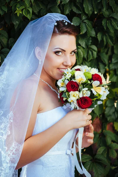 明るい花束を手で保持して美しい若い花嫁の肖像画。結婚式のお祝い。レセプション。自然緑の背景。女性一人で公園で屋外 — ストック写真