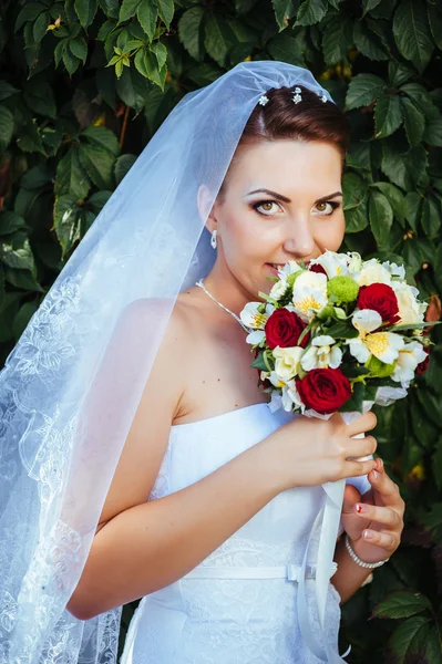 Retrato de hermosa novia joven sosteniendo ramo brillante de flores en las manos. celebración de la boda. recepción. naturaleza fondo verde. mujer sola al aire libre en el parque —  Fotos de Stock