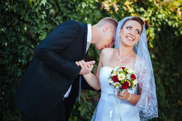 Novia y novio en el día de la boda caminando al aire libre en la naturaleza de primavera. Pareja nupcial, feliz mujer recién casada y hombre abrazándose en el parque verde. Amar pareja de boda al aire libre . — Foto de Stock