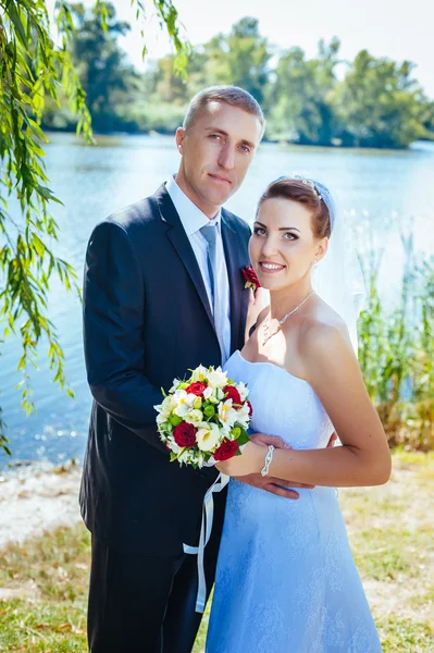 Bruid en bruidegom op huwelijksdag buiten lopen op lente aard. bruidspaar, gelukkig jonggehuwde vrouw en man omarmen in groen park. liefdevolle bruidspaar buiten. — Stockfoto