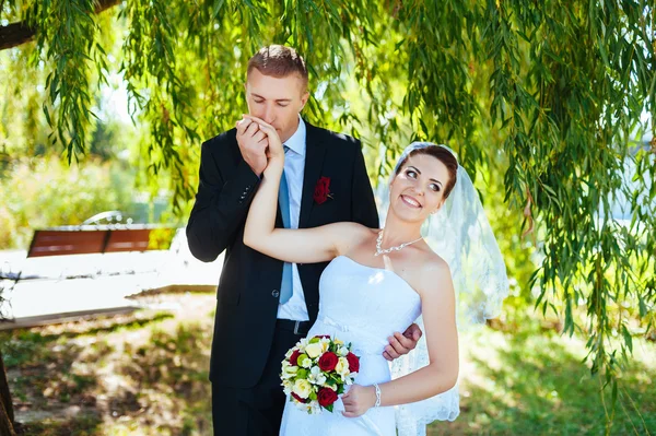 Bruid en bruidegom op huwelijksdag buiten lopen op lente aard. bruidspaar, gelukkig jonggehuwde vrouw en man omarmen in groen park. liefdevolle bruidspaar buiten. — Stockfoto