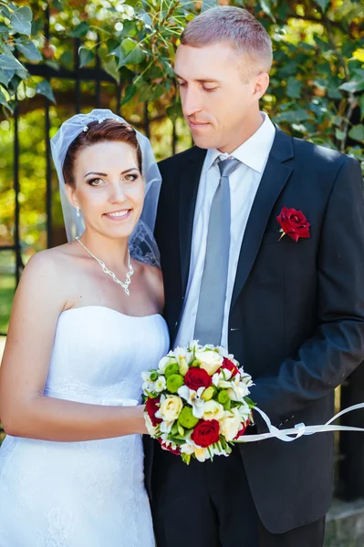 Noiva e noivo no dia do casamento andando ao ar livre na natureza de primavera. Casal nupcial, mulher recém-casada feliz e homem abraçando no parque verde. Casal de amor ao ar livre . — Fotografia de Stock