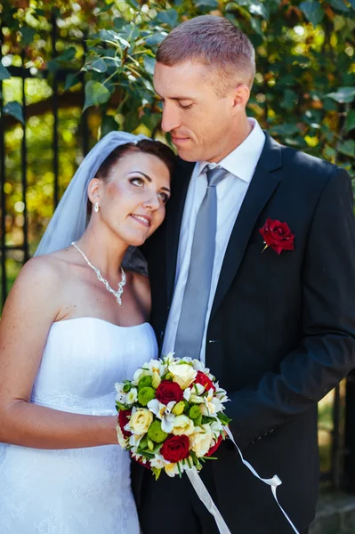 Novia y novio en el día de la boda caminando al aire libre en la naturaleza de primavera. Pareja nupcial, feliz mujer recién casada y hombre abrazándose en el parque verde. Amar pareja de boda al aire libre . — Foto de Stock