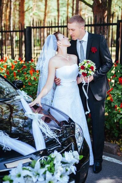 Кавказская невеста и жених возле винтажного свадебного автомобиля . — стоковое фото