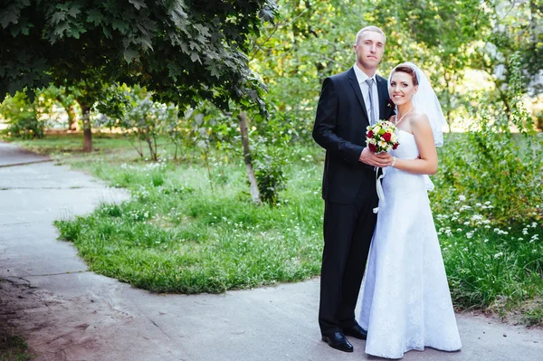 Νύφη και γαμπρός στο περπάτημα σε εξωτερικούς χώρους για την ημέρα του γάμου άνοιξη φύση. νυφικό ζευγάρι, γυναίκα ευτυχισμένη νεόνυμφο και άνθρωπος, αγκαλιάζοντας σε καταπράσινο πάρκο. αγαπώντας το γαμήλιο ζεύγος εξωτερική. — Φωτογραφία Αρχείου