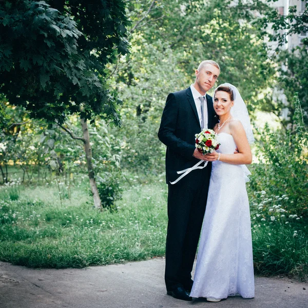 Braut und Bräutigam am Hochzeitstag beim Spaziergang in der Natur des Frühlings. Brautpaar, glückliche frisch vermählte Frau und Mann umarmen sich im grünen Park. Liebendes Hochzeitspaar im Freien. — Stockfoto