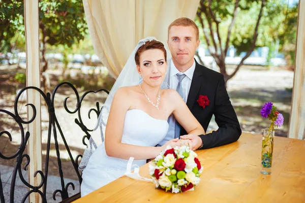Sposo e sposo in posa al tavolo da banchetto decorato nel parco in estate. Goditi un momento di felicità e amore. Una serie di foto nel mio portfolio — Foto Stock