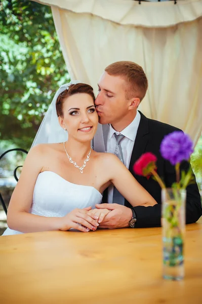 Bruid en bruidegom poseren aan de ingerichte feestzaal tafel in het park in de zomer. Geniet van een moment van geluk en liefde. Een reeks van foto's in mijn portefeuille — Stockfoto