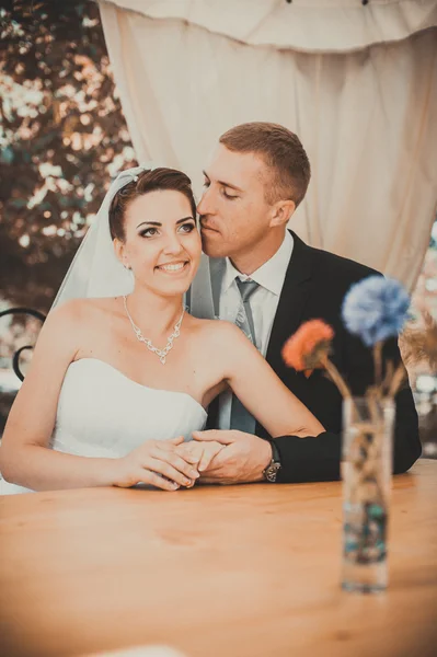 Bruden och brudgummen poserar på tabellen inredda bankett i parken i sommar. Njut en stund av lycka och kärlek. En serie bilder i min portfolio — Stockfoto