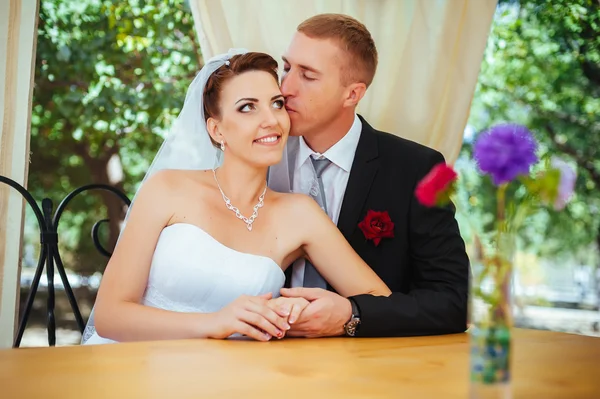 Bruid en bruidegom poseren aan de ingerichte feestzaal tafel in het park in de zomer. Geniet van een moment van geluk en liefde. Een reeks van foto's in mijn portefeuille — Stockfoto