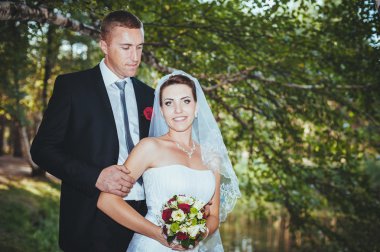 Deniz kenarında bir düğün. Balayı. Gelin ve damat Gölü kıyısına sarılma. damat ve gelin yeşil bir gölde sarılma. Damat ve gelin bir parkta. gelinlik. Gelin düğün buket çiçek.