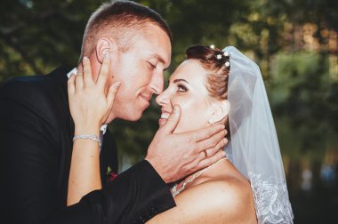 Deniz kenarında bir düğün. Balayı. Gelin ve damat Gölü kıyısına sarılma. damat ve gelin yeşil bir gölde sarılma. Damat ve gelin bir parkta. gelinlik. Gelin düğün buket çiçek.