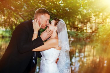 Deniz kenarında bir düğün. Balayı. Gelin ve damat Gölü kıyısına sarılma. damat ve gelin yeşil bir gölde sarılma. Damat ve gelin bir parkta. gelinlik. Gelin düğün buket çiçek.