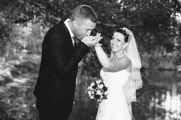 Un mariage près de la mer. Lune de miel. Les mariés se câlinent sur la rive du lac. marié et mariée étreignant sur un lac vert. Groom and Bride dans un parc. robe de mariée. Bouquet de mariage nuptial de fleurs . — Photo