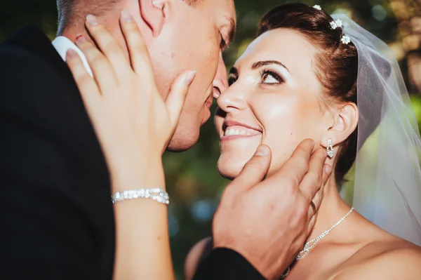 Um casamento à beira-mar. Lua-de-mel. A noiva e o noivo abraçados na margem do lago. noivo e noiva abraçando em um lago verde. O noivo e a noiva num parque. Vestido de noiva. Buquê de casamento nupcial de flores . — Fotografia de Stock